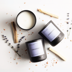 Three 'Awaken' candles on a light surface with lavender and wooden sticks.