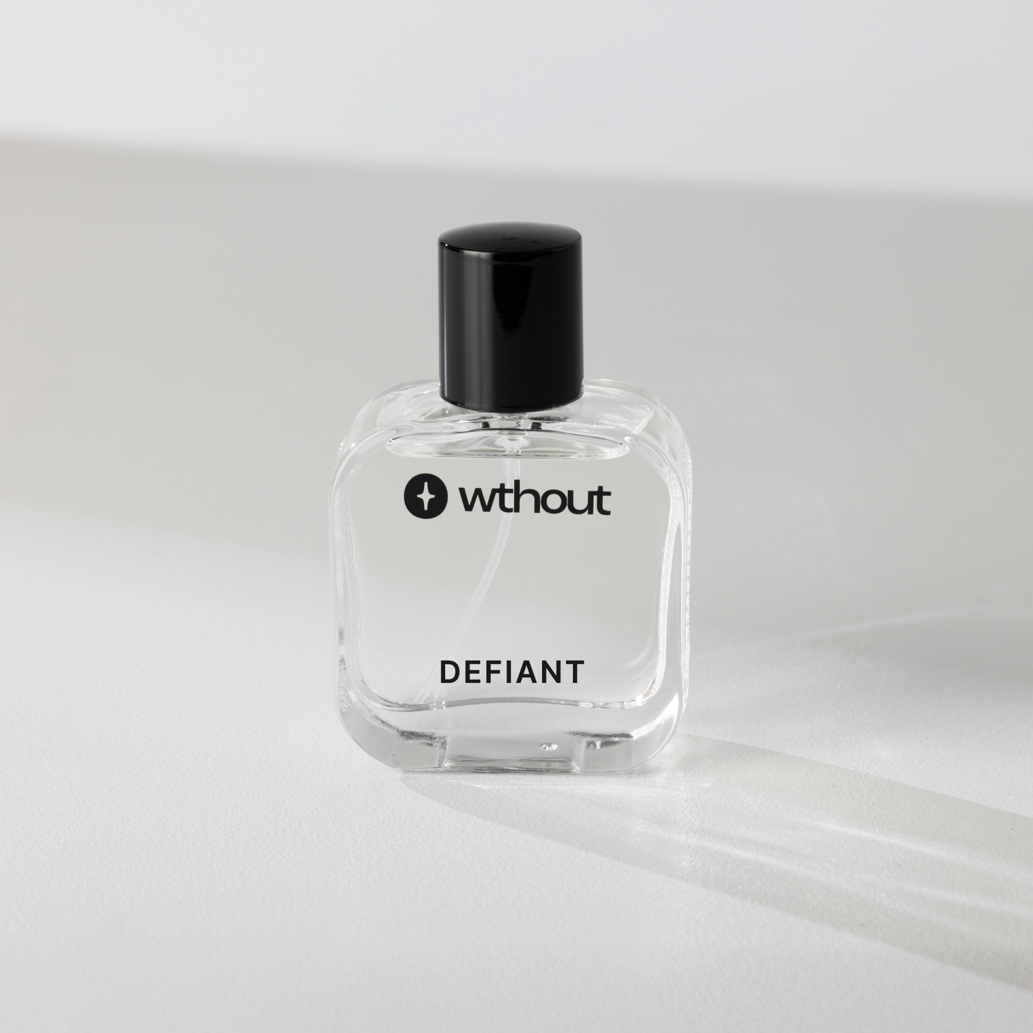 Clear perfume bottle labeled 'without' with 'DEFIANT' on a white background