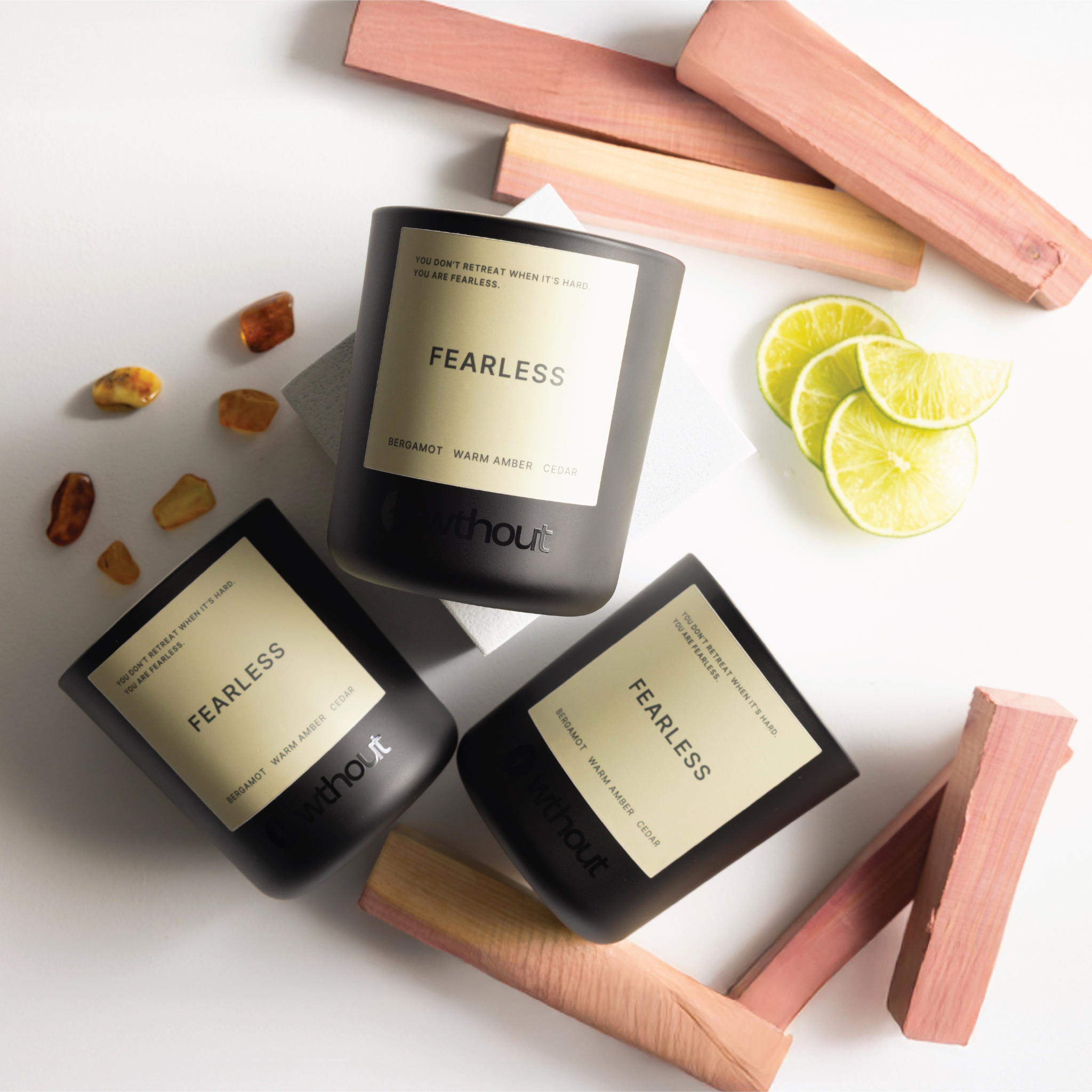 Three candles labeled 'Fearless' on a white surface with wooden blocks and lime slices.