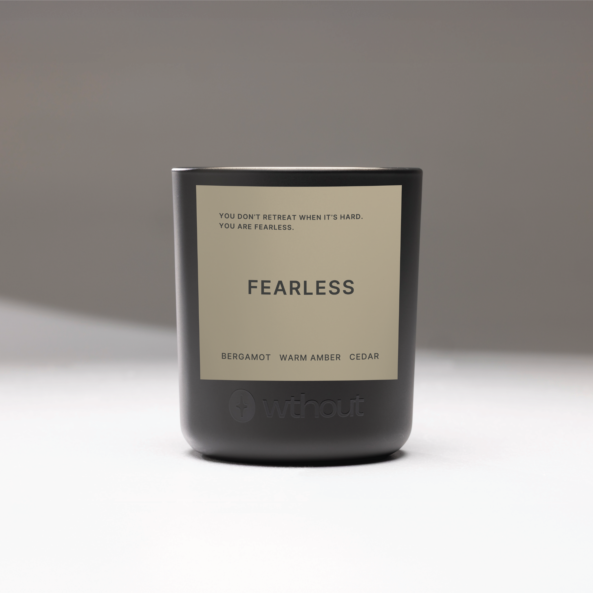 Candle with 'FEARLESS' label and motivational quote on a gray background